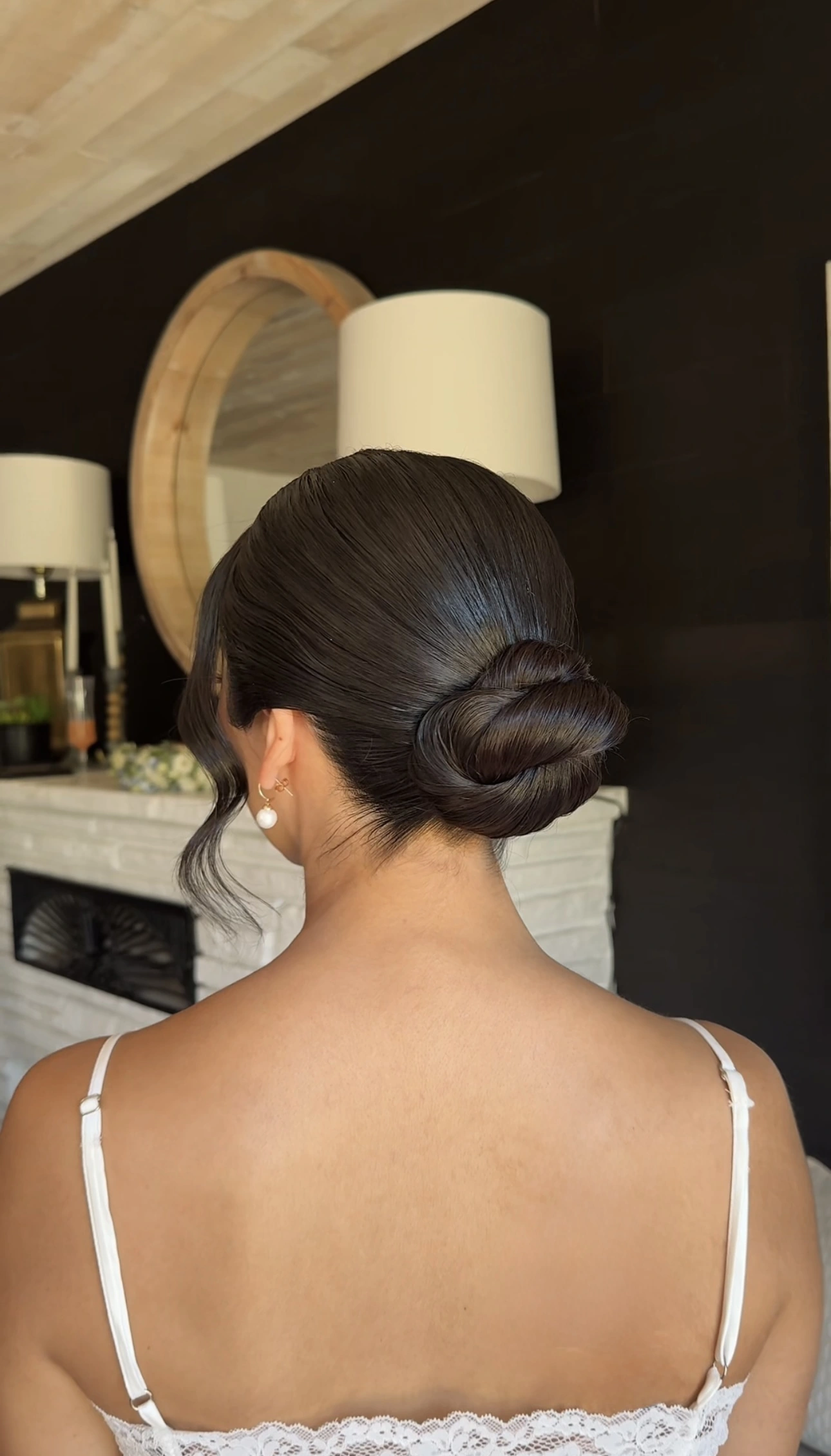 Polished low bridal bun with softly framed strands