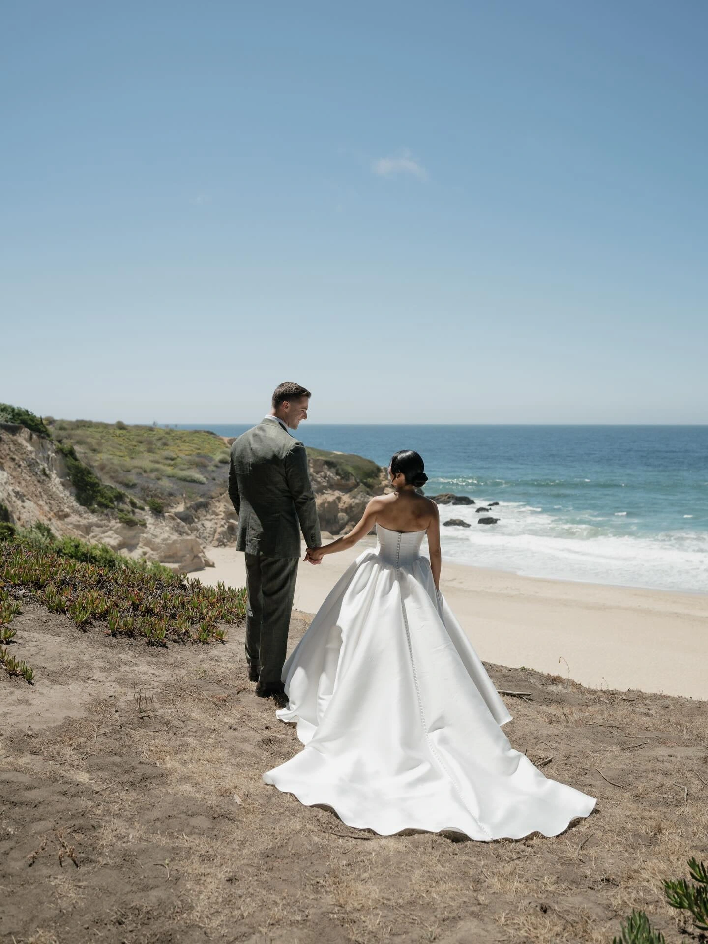 Bride and groom overlooking the ocean with a flowing bridal train