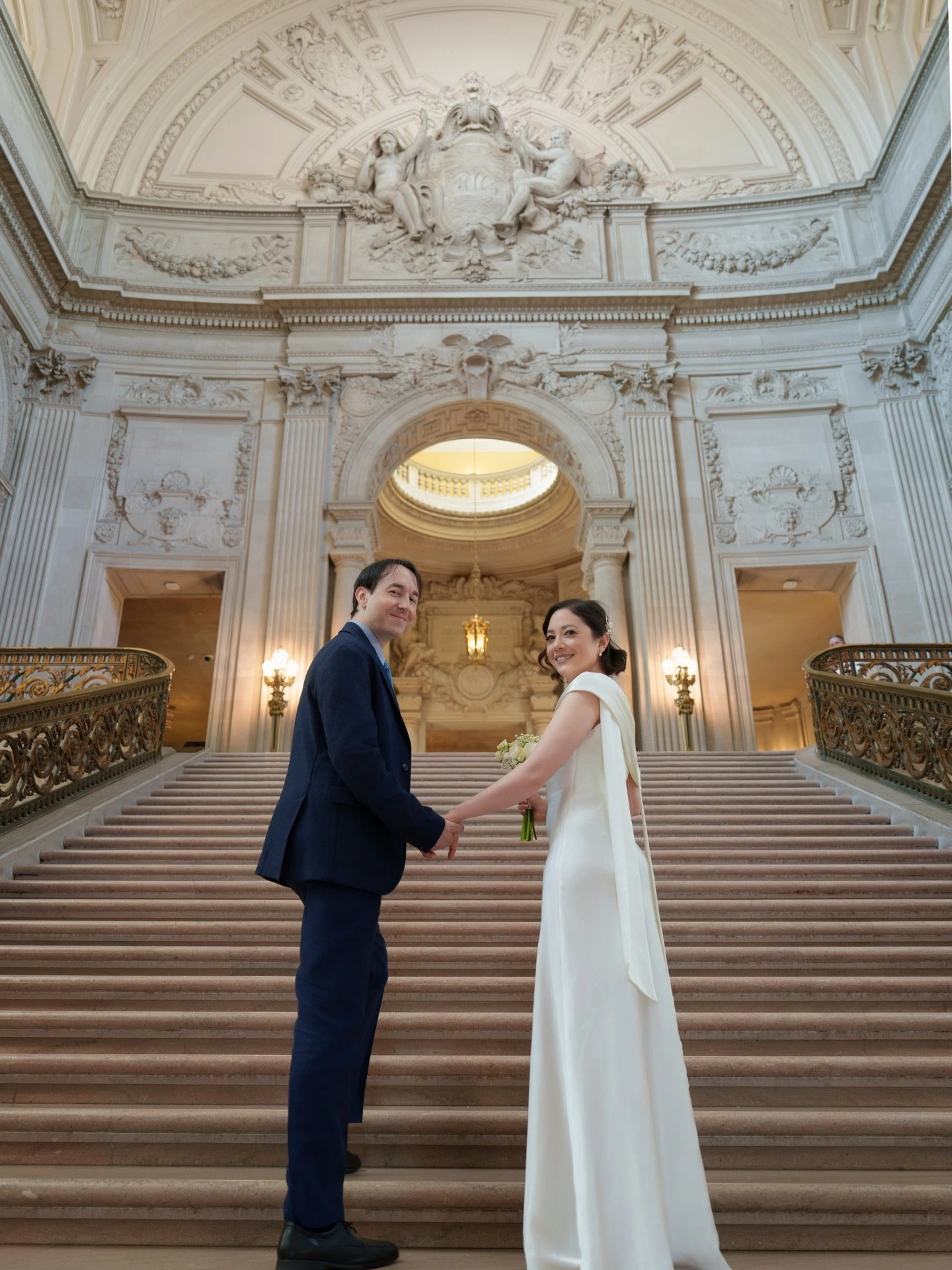 Bride with a polished updo and groom on an ornate staircase