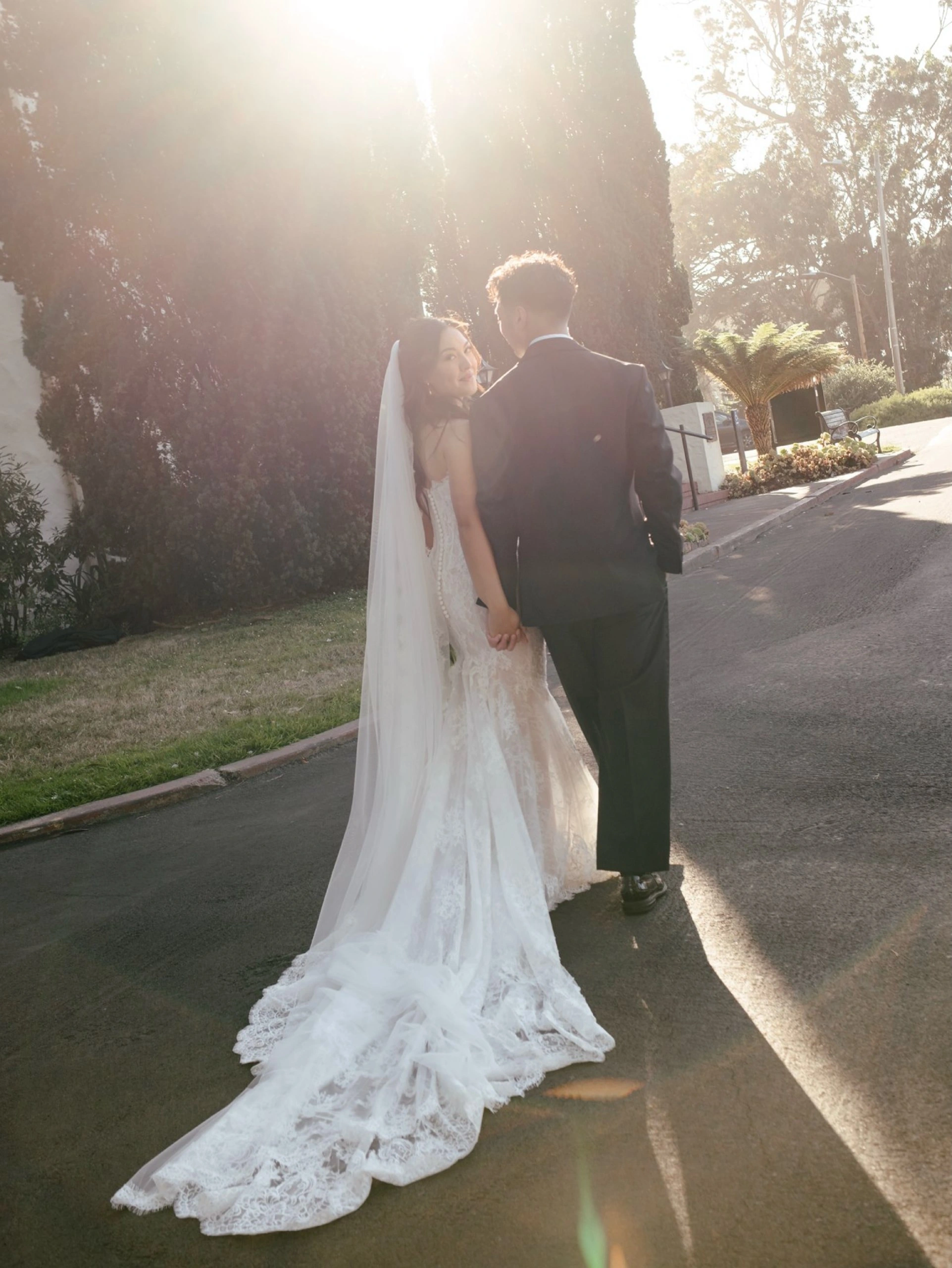 Bride and groom walking hand in hand in warm sunlight