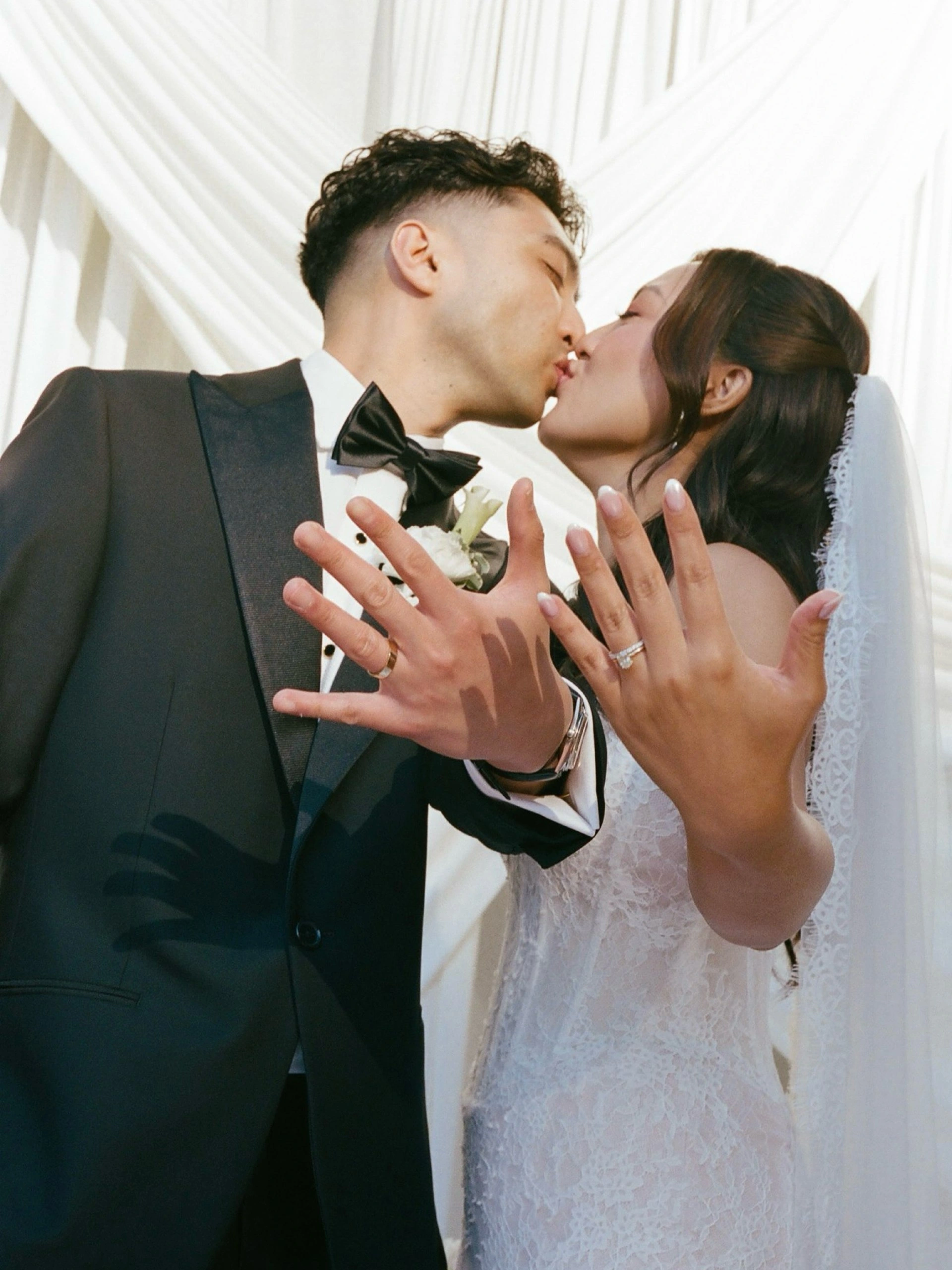 Newlyweds sharing a kiss and showing their wedding rings